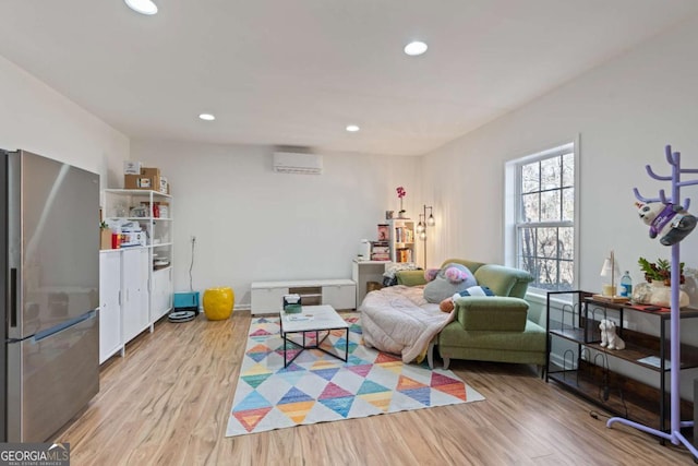 game room featuring a wall mounted air conditioner and light hardwood / wood-style flooring