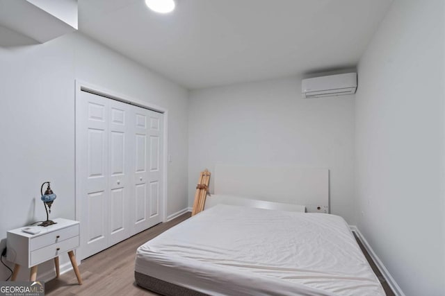 bedroom with a closet, wood-type flooring, and a wall mounted AC