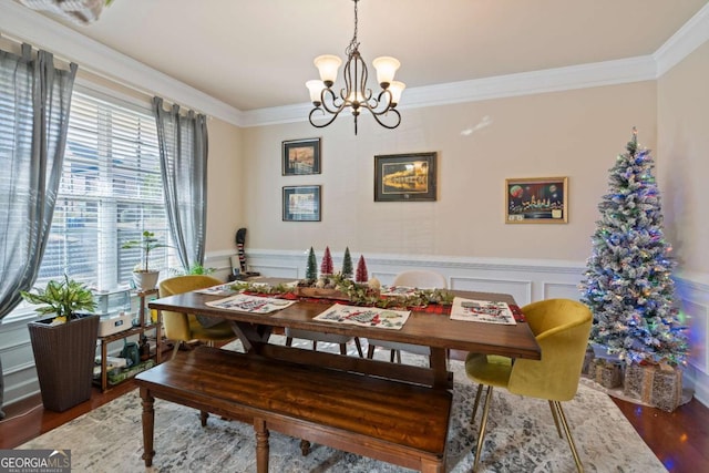 dining space with hardwood / wood-style flooring, ornamental molding, and a chandelier