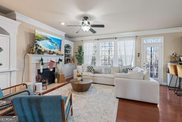 living room featuring a fireplace, dark hardwood / wood-style floors, ceiling fan, and crown molding