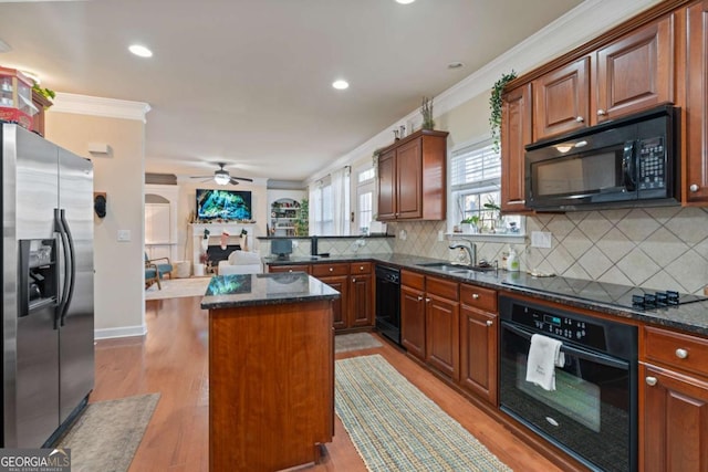 kitchen featuring ceiling fan, sink, a center island, light hardwood / wood-style flooring, and black appliances