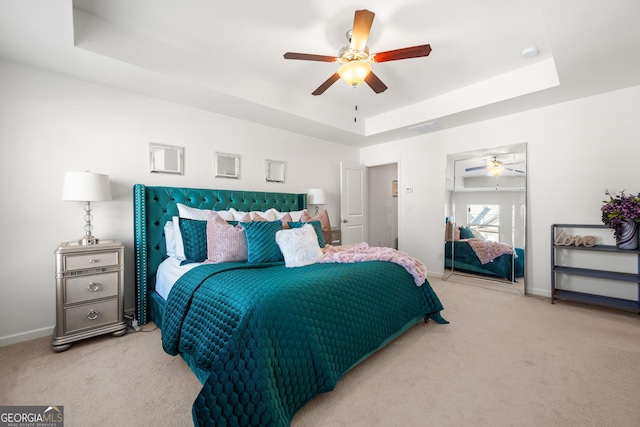 bedroom with light colored carpet, a raised ceiling, and ceiling fan