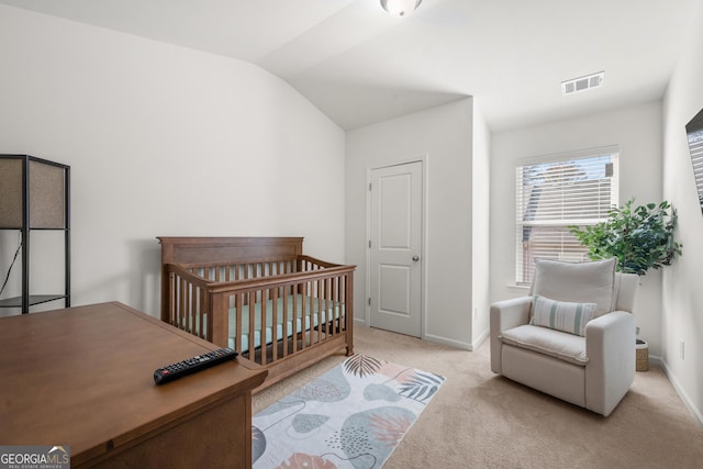 carpeted bedroom featuring a crib and vaulted ceiling