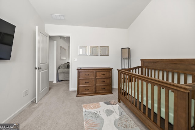 bedroom featuring light colored carpet and a nursery area