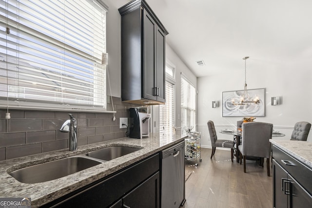 kitchen with sink, hanging light fixtures, stainless steel dishwasher, light hardwood / wood-style floors, and a chandelier