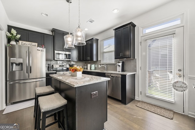 kitchen featuring a center island, stainless steel appliances, hanging light fixtures, and tasteful backsplash