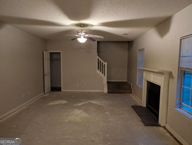 unfurnished living room featuring ceiling fan, a textured ceiling, and concrete floors