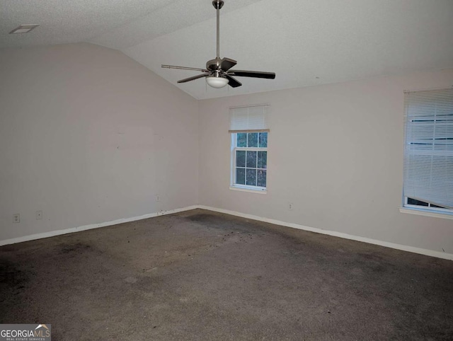 carpeted empty room with a textured ceiling, ceiling fan, and vaulted ceiling