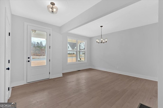 foyer entrance featuring light hardwood / wood-style floors, beam ceiling, and an inviting chandelier