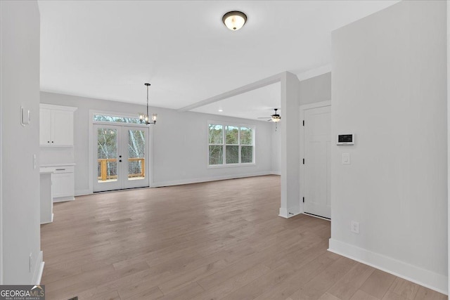 interior space with french doors, ceiling fan with notable chandelier, and light hardwood / wood-style flooring