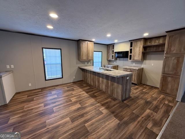 kitchen with kitchen peninsula, a textured ceiling, dark hardwood / wood-style flooring, and sink