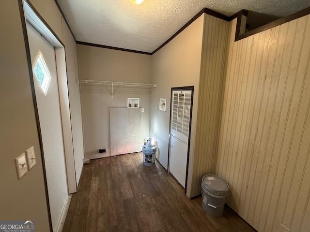 washroom featuring a textured ceiling, dark hardwood / wood-style flooring, hookup for a washing machine, and wood walls