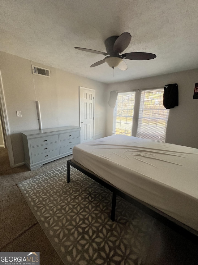 carpeted bedroom with ceiling fan and a textured ceiling