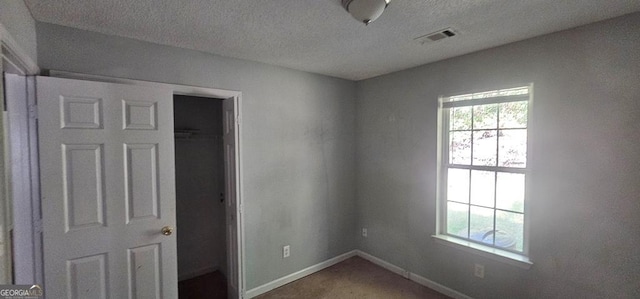 carpeted empty room featuring a textured ceiling