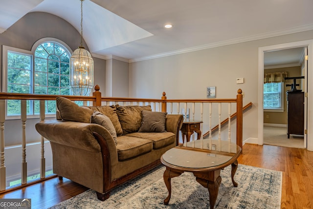 living room featuring hardwood / wood-style flooring, lofted ceiling, crown molding, and a chandelier