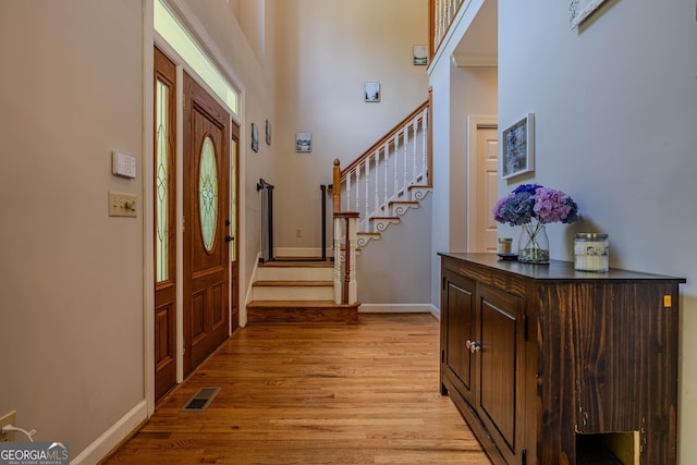 foyer with light wood-type flooring and a towering ceiling