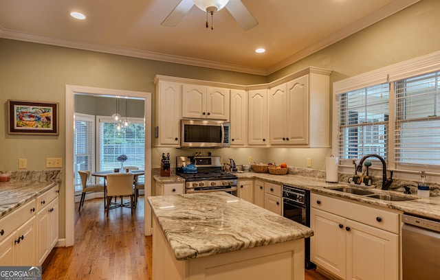 kitchen with white cabinetry, sink, stainless steel appliances, light hardwood / wood-style floors, and ornamental molding