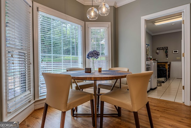 dining area featuring light wood-type flooring and crown molding