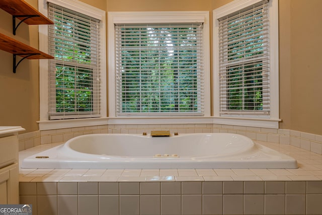 bathroom featuring a relaxing tiled tub and vanity