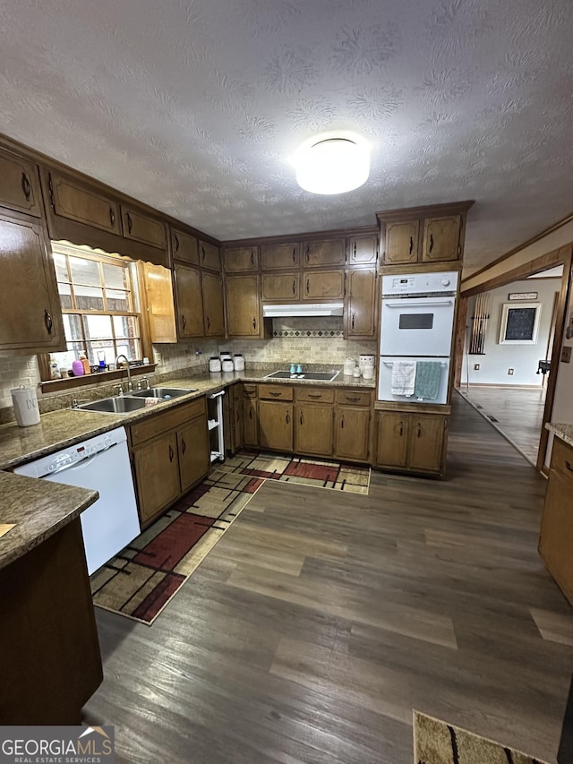 kitchen with a textured ceiling, white dishwasher, dark hardwood / wood-style floors, and sink