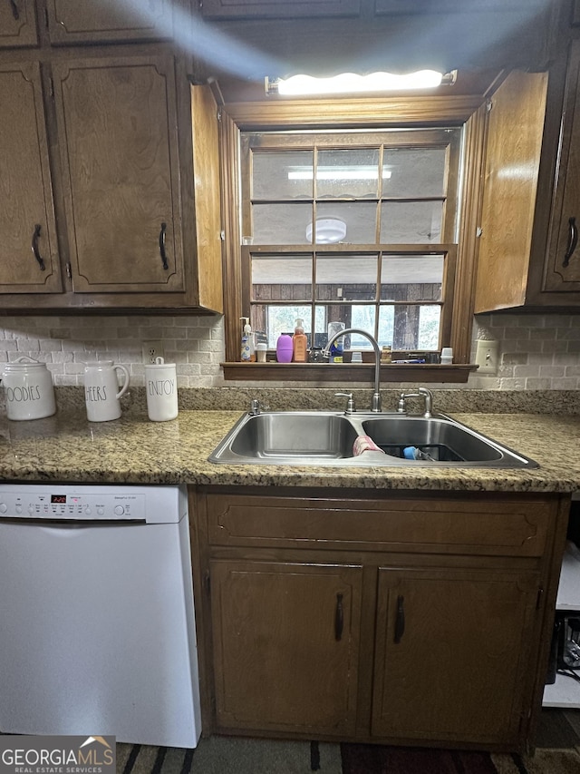 kitchen with decorative backsplash, white dishwasher, and sink