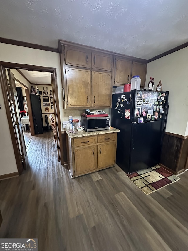 kitchen featuring a textured ceiling, black fridge, crown molding, and dark hardwood / wood-style floors