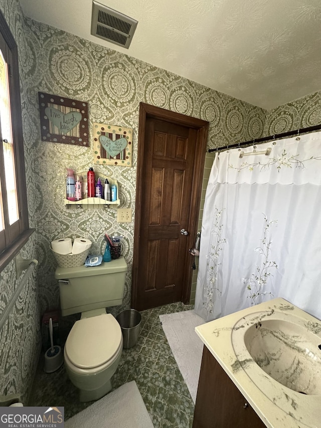 bathroom with vanity, a textured ceiling, toilet, and curtained shower