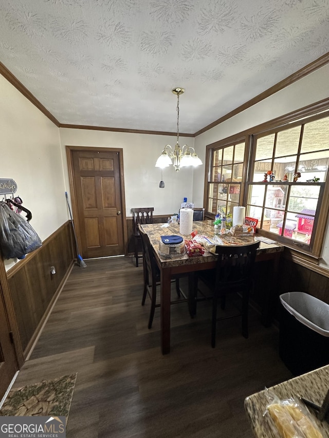 dining area featuring dark hardwood / wood-style floors, a textured ceiling, wooden walls, and a chandelier