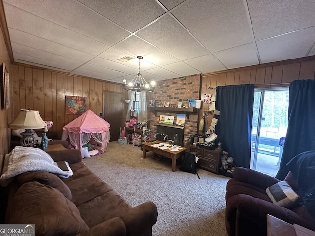 carpeted living room with a paneled ceiling, a notable chandelier, and wood walls