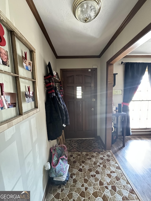 entrance foyer with a textured ceiling, dark hardwood / wood-style flooring, and ornamental molding