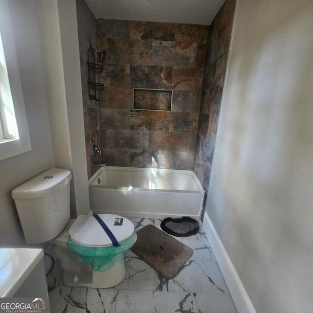 bathroom with tiled shower / bath combo and toilet