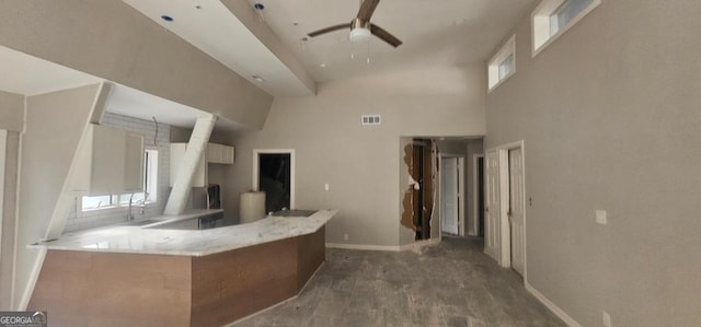 kitchen with kitchen peninsula, a high ceiling, hardwood / wood-style flooring, and ceiling fan