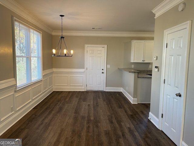 unfurnished dining area featuring ornamental molding, dark wood-type flooring, and a chandelier