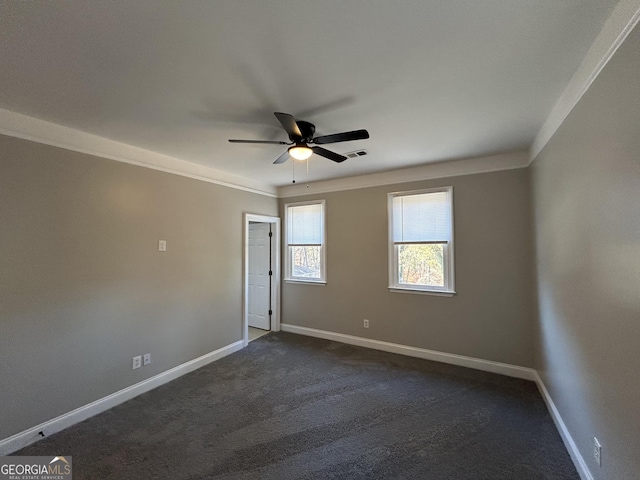 empty room featuring crown molding, ceiling fan, and dark carpet