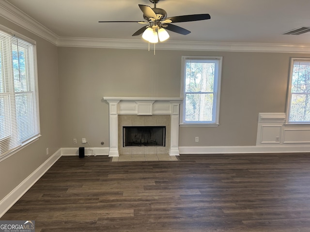 unfurnished living room featuring ceiling fan, a healthy amount of sunlight, dark wood-type flooring, and a tile fireplace