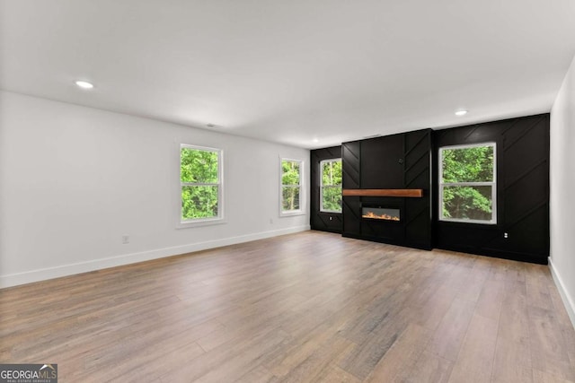 unfurnished living room featuring a large fireplace and light hardwood / wood-style flooring