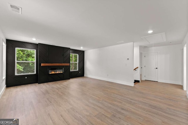 unfurnished living room with a large fireplace and light wood-type flooring