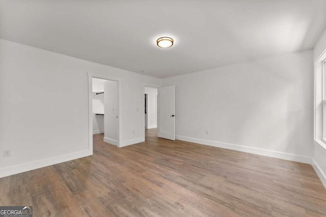 unfurnished bedroom with hardwood / wood-style floors, a spacious closet, and a closet