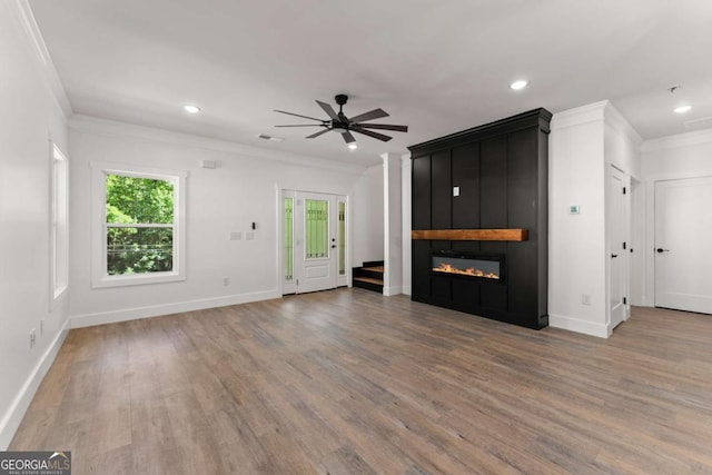 unfurnished living room with ceiling fan, a large fireplace, wood-type flooring, and ornamental molding