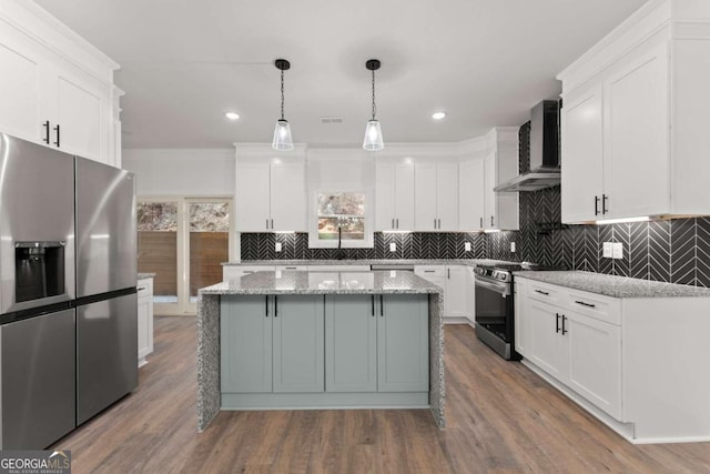 kitchen with light stone countertops, appliances with stainless steel finishes, wall chimney exhaust hood, a center island, and white cabinetry