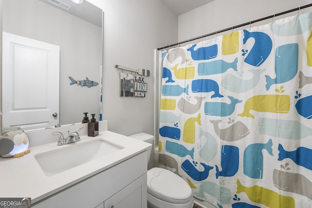 bathroom featuring toilet, vanity, and walk in shower