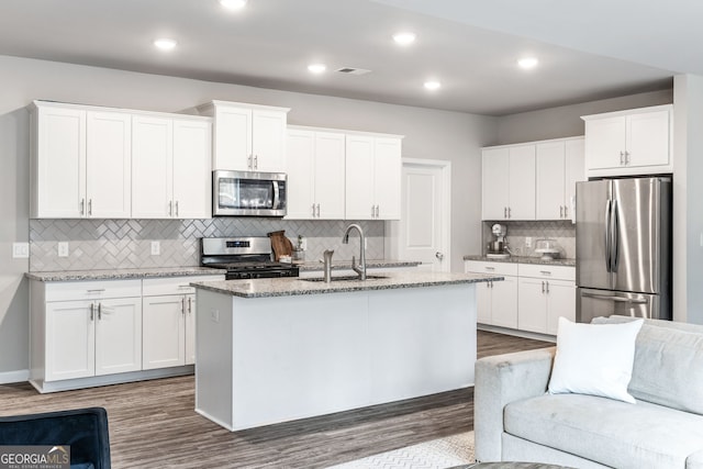 kitchen featuring sink, white cabinetry, a kitchen island with sink, stainless steel appliances, and light stone counters