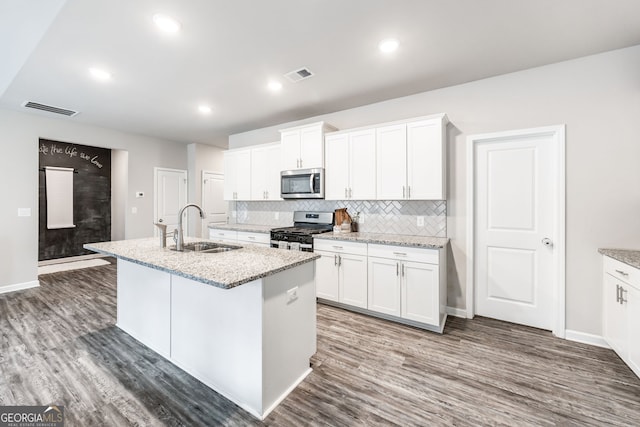 kitchen with stainless steel appliances, a kitchen island with sink, white cabinetry, and sink