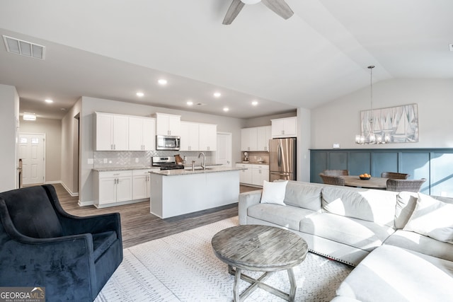 living room featuring hardwood / wood-style flooring, sink, lofted ceiling, and ceiling fan with notable chandelier