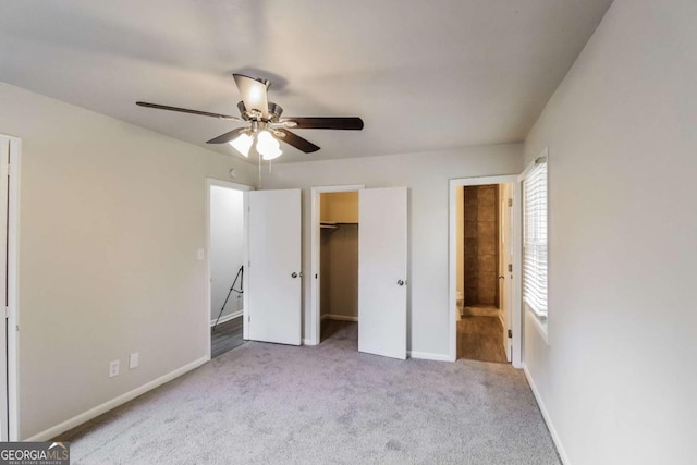 unfurnished bedroom featuring ceiling fan, a closet, light colored carpet, and a spacious closet