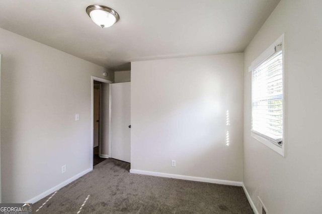 unfurnished room with dark colored carpet