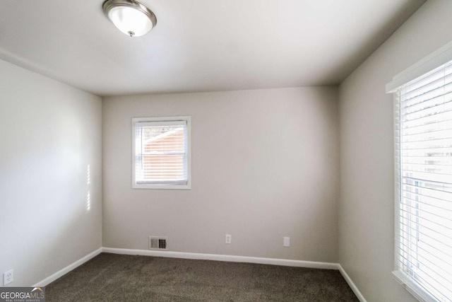 unfurnished room featuring dark carpet