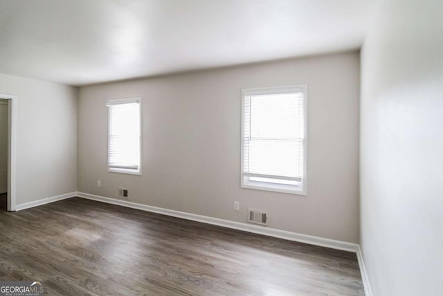 spare room with dark wood-type flooring and a healthy amount of sunlight