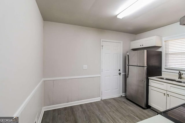 kitchen featuring stainless steel fridge, white cabinetry, sink, and light hardwood / wood-style flooring