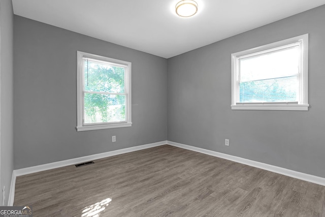 unfurnished bedroom featuring hardwood / wood-style floors, ensuite bathroom, and a closet